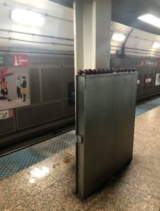 Row of red apples on a large metal box in a subway station